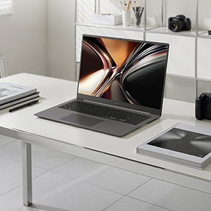 책상위에 LG gram Pro 실버 모델의 노트북이 비스듬하게 펼쳐져 있습니다.