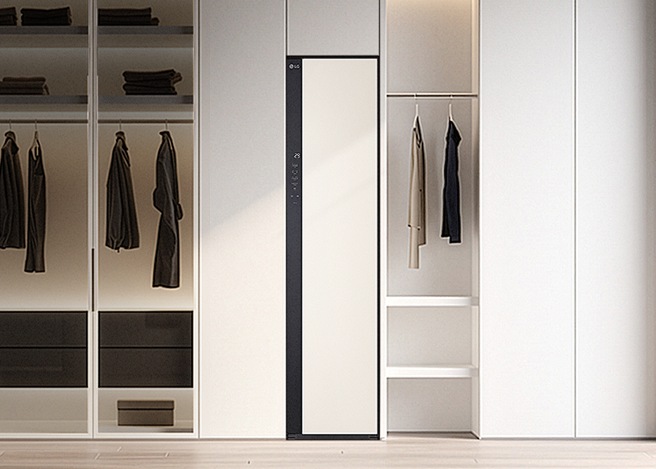 모던한 드레스룸 인테리어 중앙에 설치된 LG 스타일러와 주변의 오픈형 옷장, 가죽 의자가 조화를 이룬 연출 이미지.